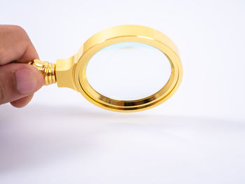 Close-up of hand holding eyeglasses against white background