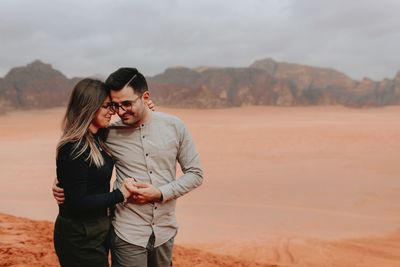 Young couple standing on landscape against sky