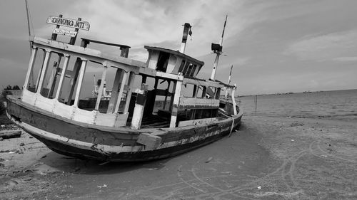 Boat moored on beach against sky