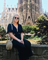 Woman sitting on railing against sagrada familia