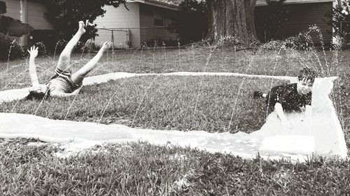 Siblings playing on water slide in lawn