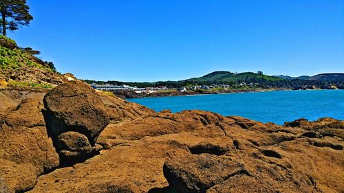 Scenic view of sea and mountains against clear blue sky