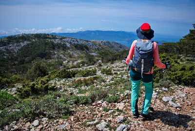 Rear view of man walking on mountain against sky