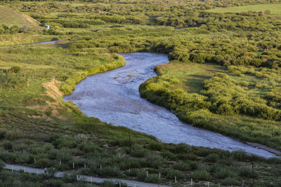 The quiet winding river is flanked by green and charming prairie