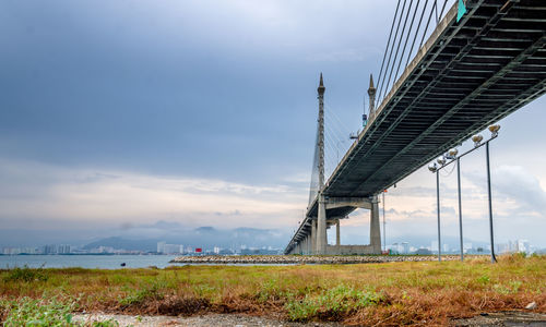 Low angle view of bridge over field against sky