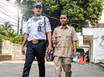 Full length of a young man standing against trees in city