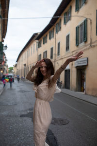 Happy woman dabbing on street against building