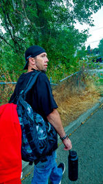 Side view of man looking away while standing against trees