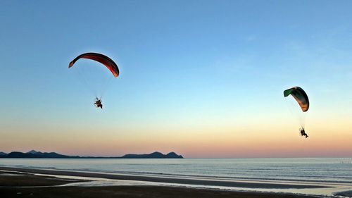 Kite flying over sea against clear sky