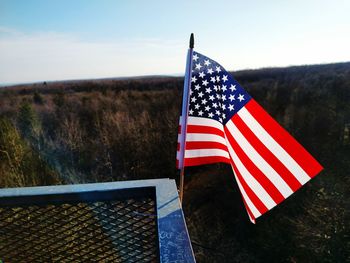 American flag on railing by landscape against sky