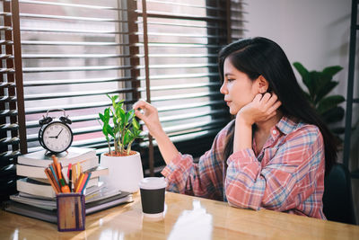 Side view of young woman sitting on table