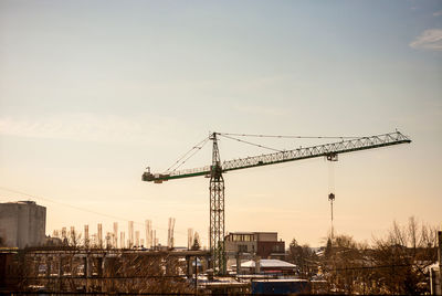 Cranes at construction site against sky during sunset