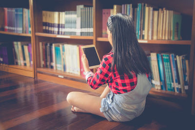 Girl using digital tablet while sitting in library