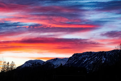 Scenic view of snowcapped mountains against orange sky