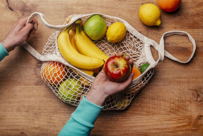 High angle view of hand holding apple on table