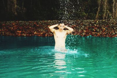 Man standing by swimming pool in forest