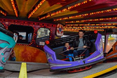 Father with son enjoying carousel at amusement park