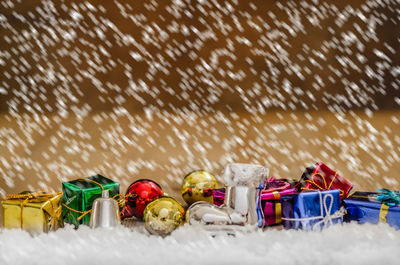 Close-up of multi colored gifts during snowfall