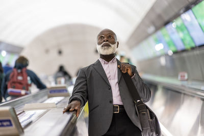 Contemplative businessman moving down on escalator at subway station