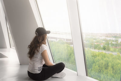 Side view of woman looking through window