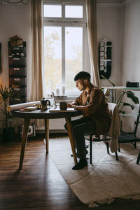 Young male freelancer working on laptop while sitting at home office