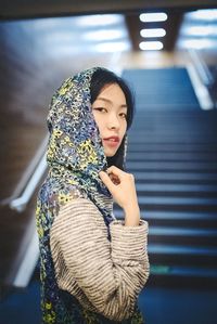 Portrait of young woman standing against wall