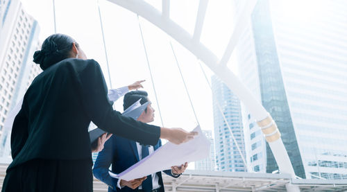 Business colleagues looking at buildings while standing in city