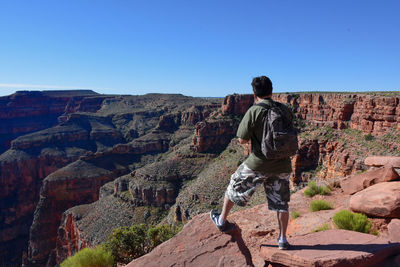 Full length of woman standing on rock against clear sky