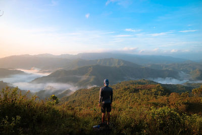 Rear view of man looking at mountains against sky