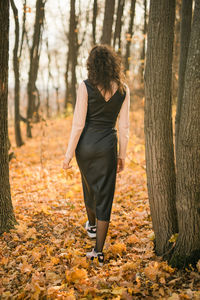 Rear view of woman standing in forest during autumn