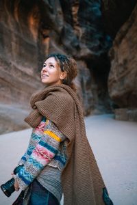 Young woman looking away while standing in snow