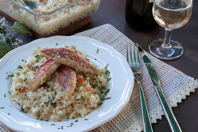 Baked gurnard fillet with rice on a plate on the table.