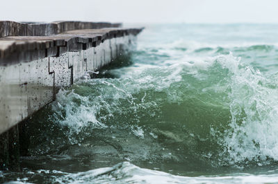 Close-up of waves breaking against pier