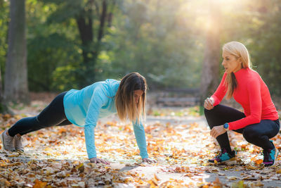 Personal fitness trainer using smart watch during training in the park. woman doing plank.