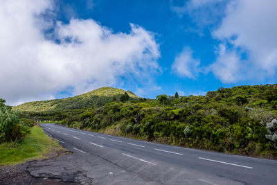 Road amidst green landscape against sky