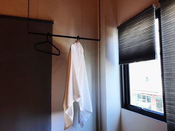 Towel hanging from coathanger on rack by window at home