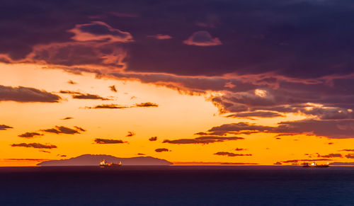 Scenic view of sea against dramatic sky during sunset