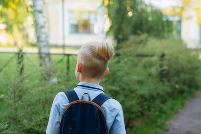 Caucasian boy walking to school wearing school bag. begining of academic year