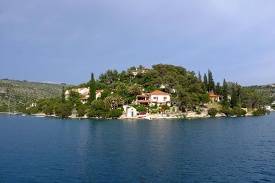 Houses by lake and buildings against sky