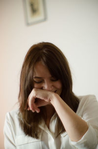 Happy woman laughing against wall