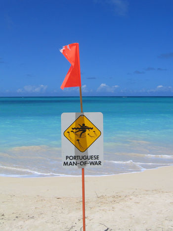 Information sign on beach against sky