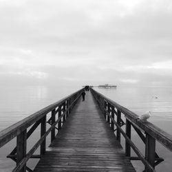 Pier on sea against cloudy sky