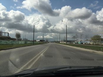 Road passing through highway against cloudy sky