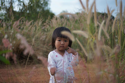 Portrait of cute girl standing on field amidst plants