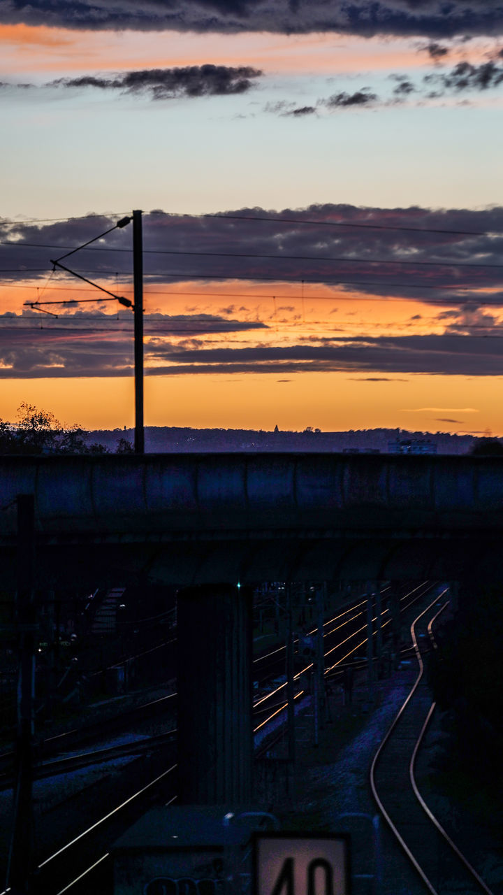 TRAIN ON RAILROAD TRACK AGAINST SKY DURING SUNSET