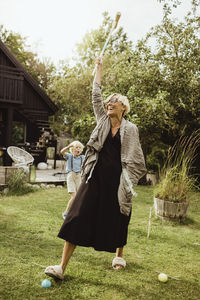 Cheerful grandmother playing polo with grandson in back yard at evening