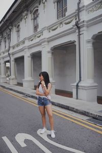 Young woman standing outdoors against building