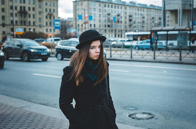 Portrait of young woman standing on street in city