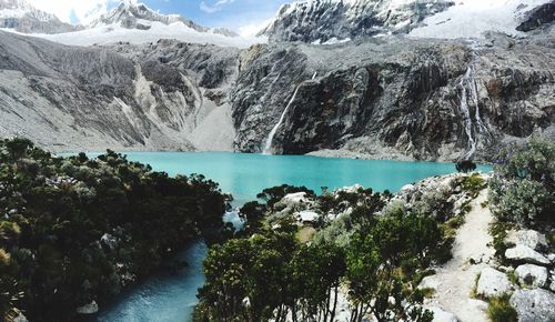 Scenic view of turquoise lake against mountains in winter