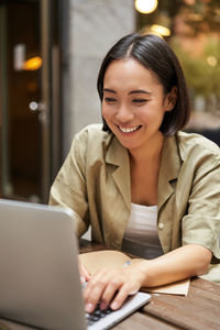 Portrait of young woman using laptop at cafe